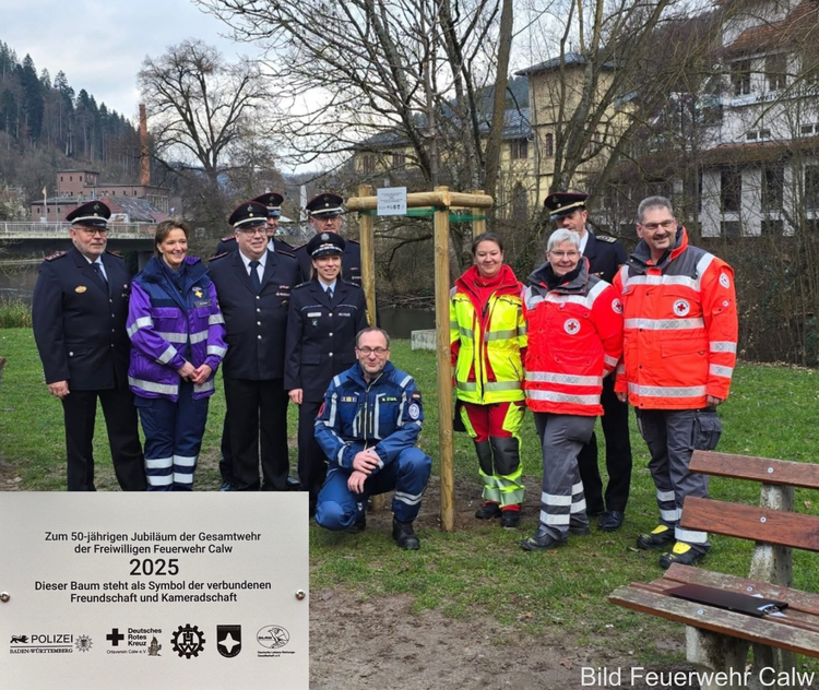 Gruppenfoto bei der Übergabe der Baumspende an die Feuerwehren Calw. Auf dem Bild stehen Vertreterinnen und Vertreter der Feuerwehren, der Polizei, der DLRG, des DRK‑Ortsvereins Calw, des THW, des Notfallnachsorgedienstes sowie weitere Beteiligte zusammen vor dem gespendeten Baum.