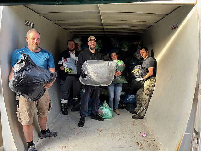 DRK‑Helfer im Abrollcontainer beim Leeren der Altkleidercontainer während der letzten Sammlung.